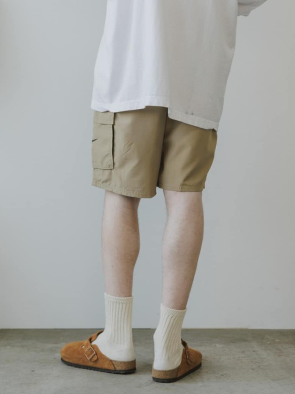 ホワイト系のTシャツ/カットソー、ブラウン系のスリッポン、ベージュ系の水着を着用したメンズの夏コーディネートの1枚目の写真