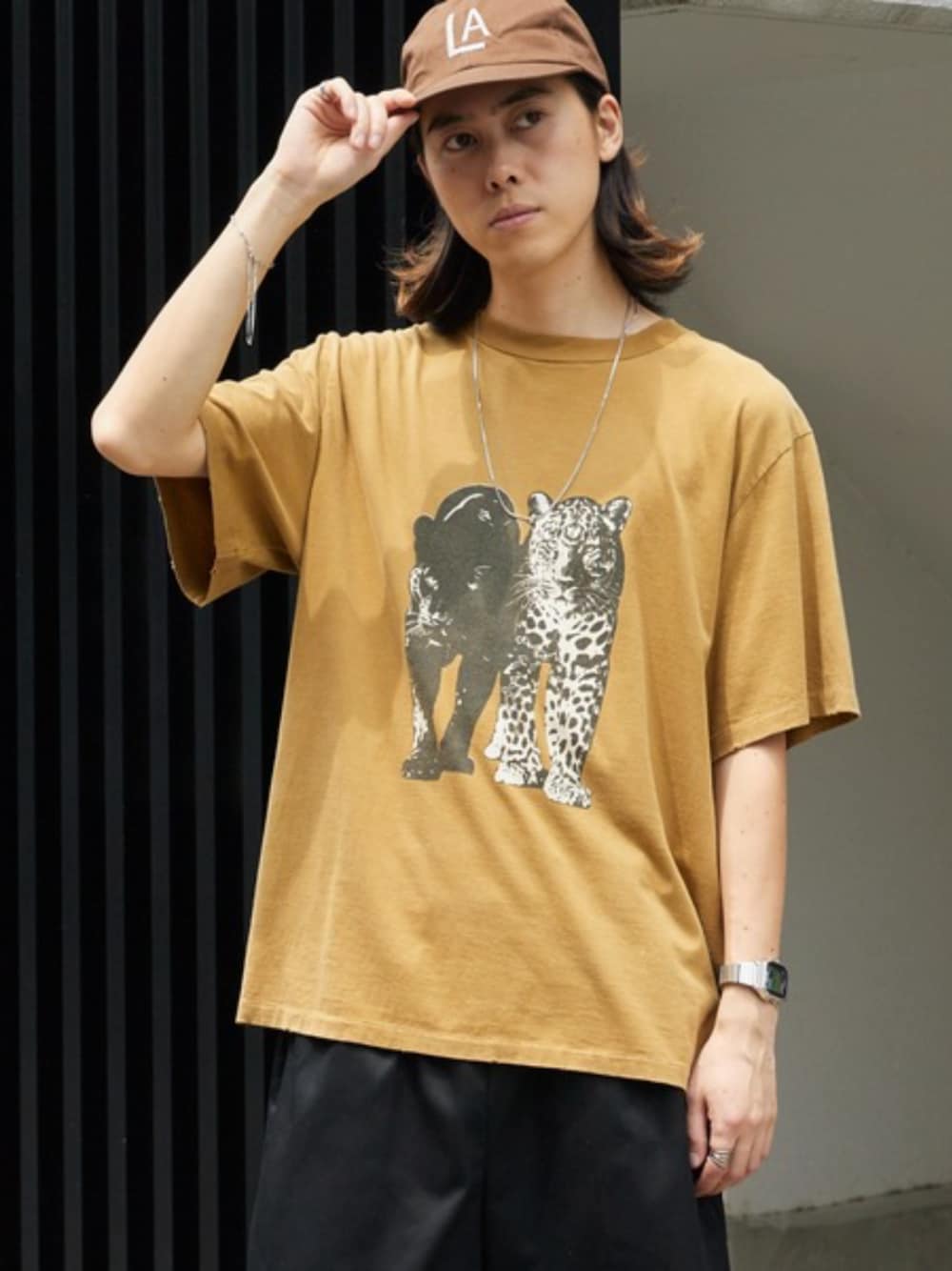 ブラック系のデニムパンツ、グリーン系のTシャツ/カットソー、ブラウン系のキャップを着用したメンズの夏コーディネートの1枚目の写真