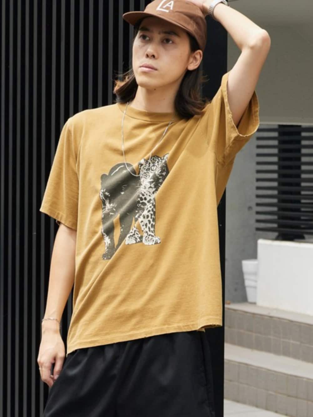 ブラック系のデニムパンツ、グリーン系のTシャツ/カットソー、ブラウン系のキャップを着用したメンズの夏コーディネートの1枚目の写真