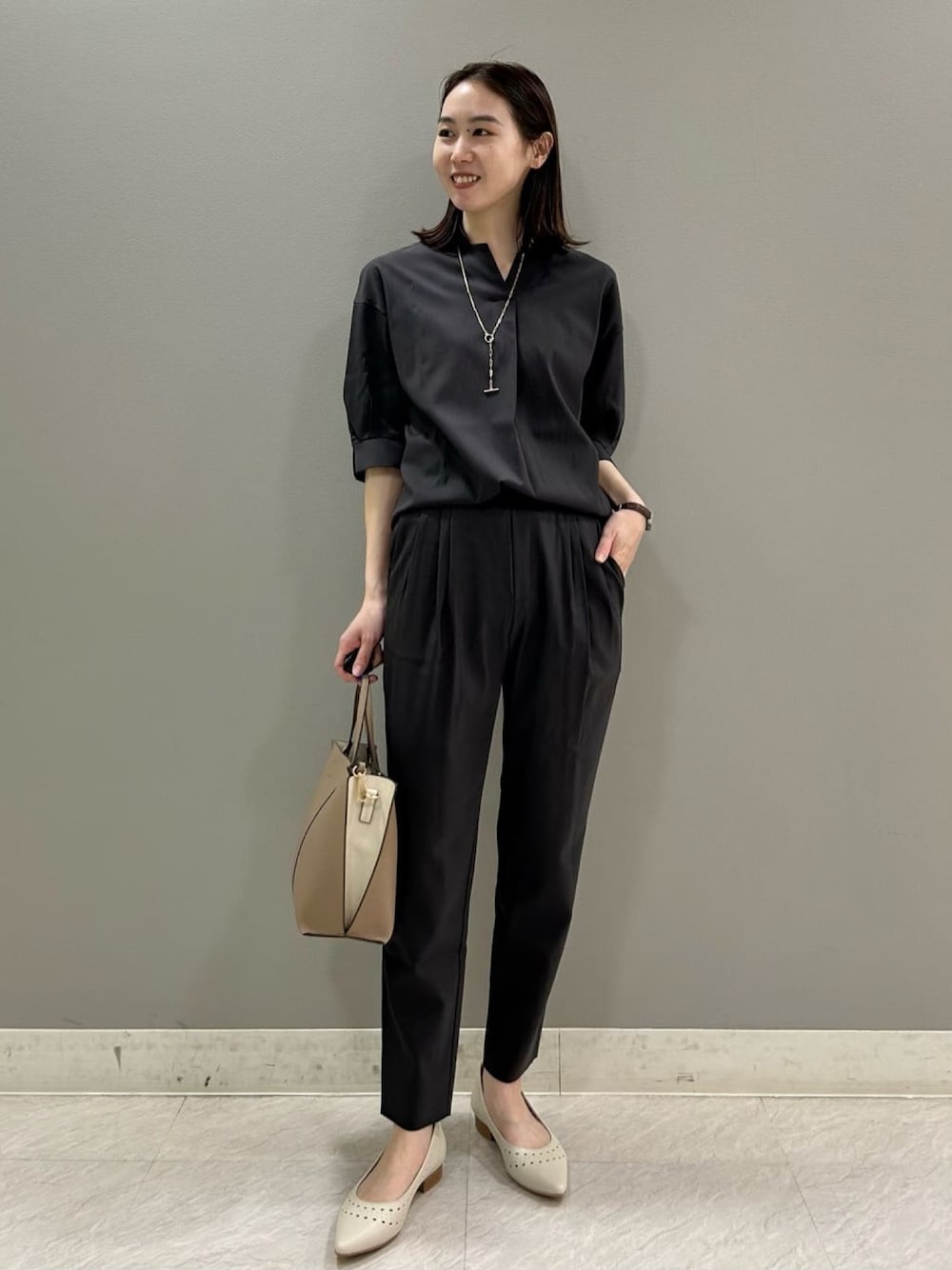 ブラック系のシャツ/ブラウス、ブラック系のその他パンツ、ベージュ系のハンドバッグを着用したレディースの夏コーディネートの1枚目の写真