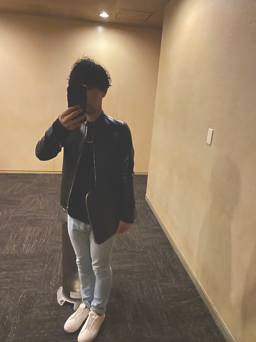 ブルー系のデニムパンツ、ホワイト系のスニーカー、ブラック系のライダースジャケットを着用したメンズの秋コーディネートの1枚目の写真