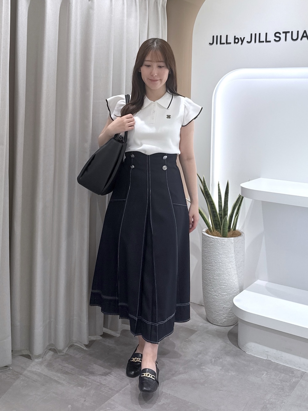 ホワイト系のニット/セーター、ブルー系のスカート、ブラック系のトートバッグを着用したレディースの夏コーディネートの1枚目の写真