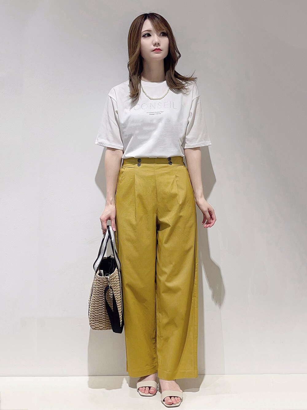 ホワイト系のTシャツ/カットソー、イエロー系のその他パンツ、ベージュ系のトートバッグを着用したレディースの春コーディネートの1枚目の写真