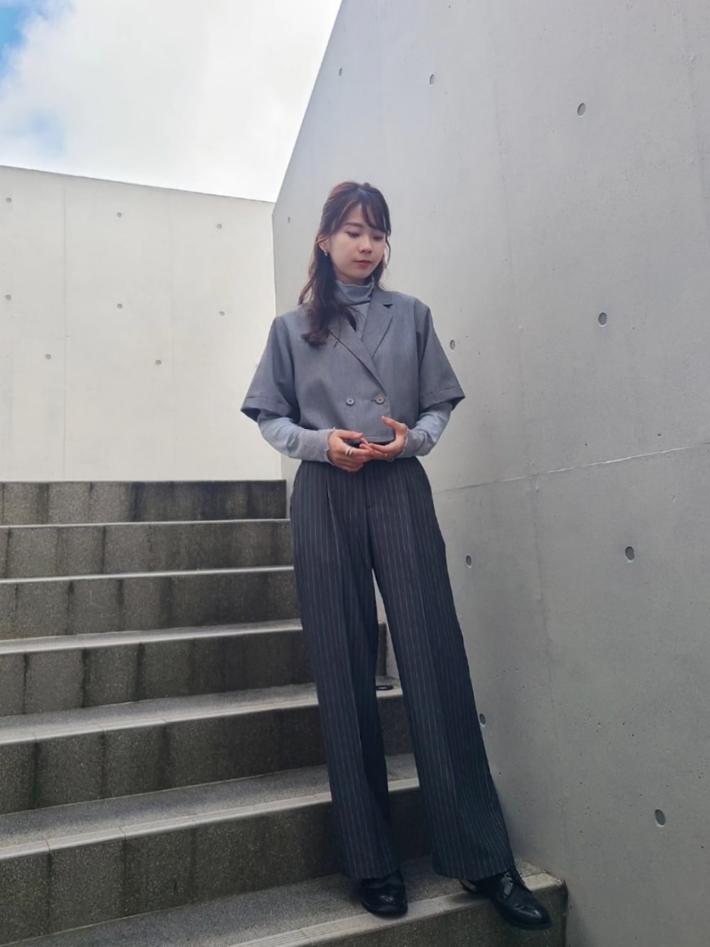 グレー系のスラックス、グレー系のセットアップ、ブルー系のTシャツ/カットソーを着用したレディースの秋コーディネートの1枚目の写真