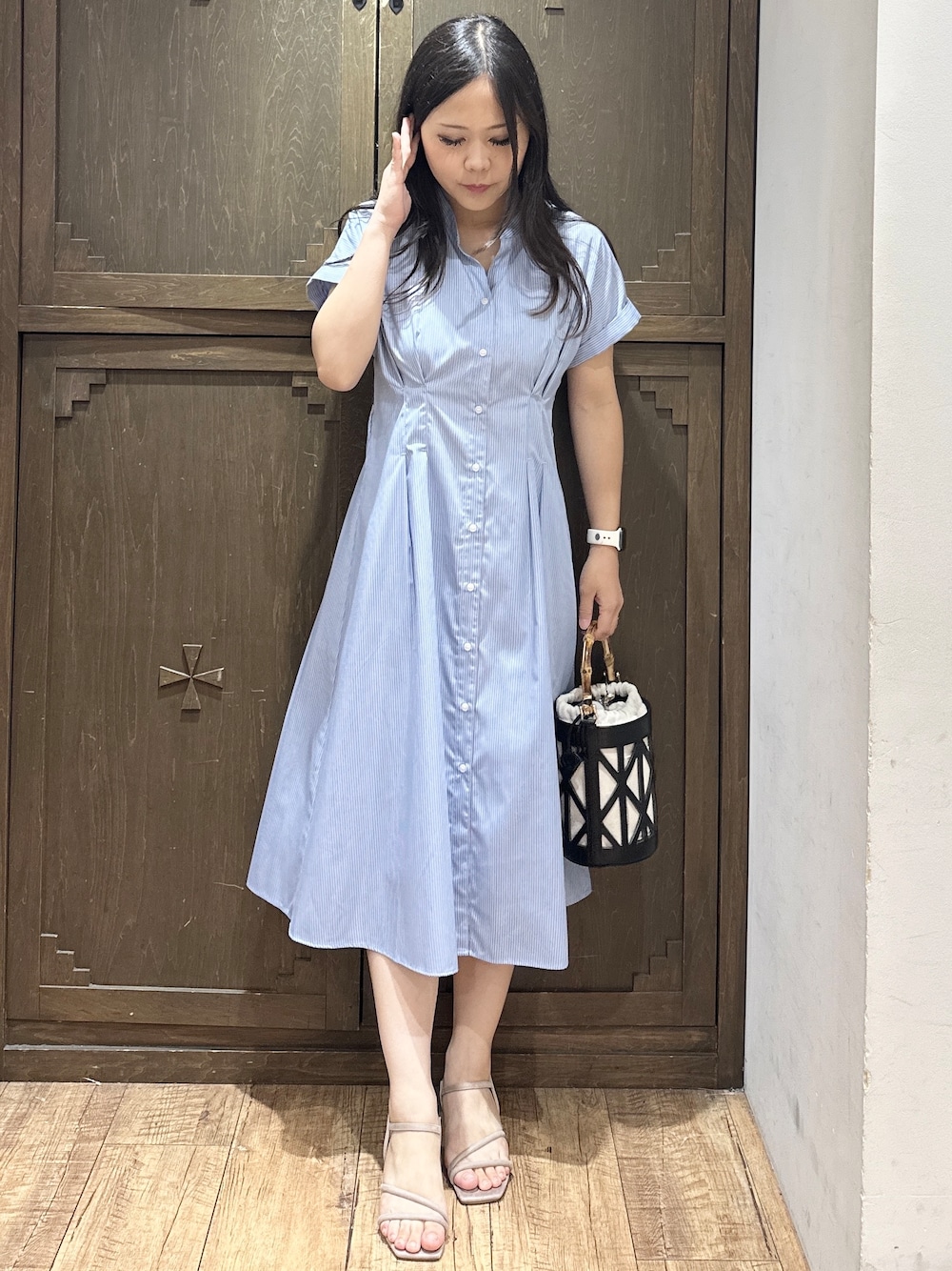 ブルー系のワンピース、ブラック系のハンドバッグ、ベージュ系のサンダルを着用したレディースの夏コーディネートの1枚目の写真