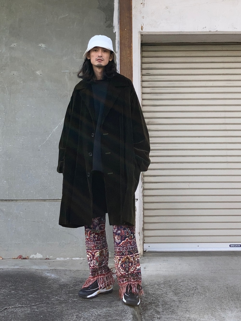 ブラック系のスウェット、ブラック系のスニーカー、ホワイト系のハットを着用したメンズの冬コーディネートの1枚目の写真