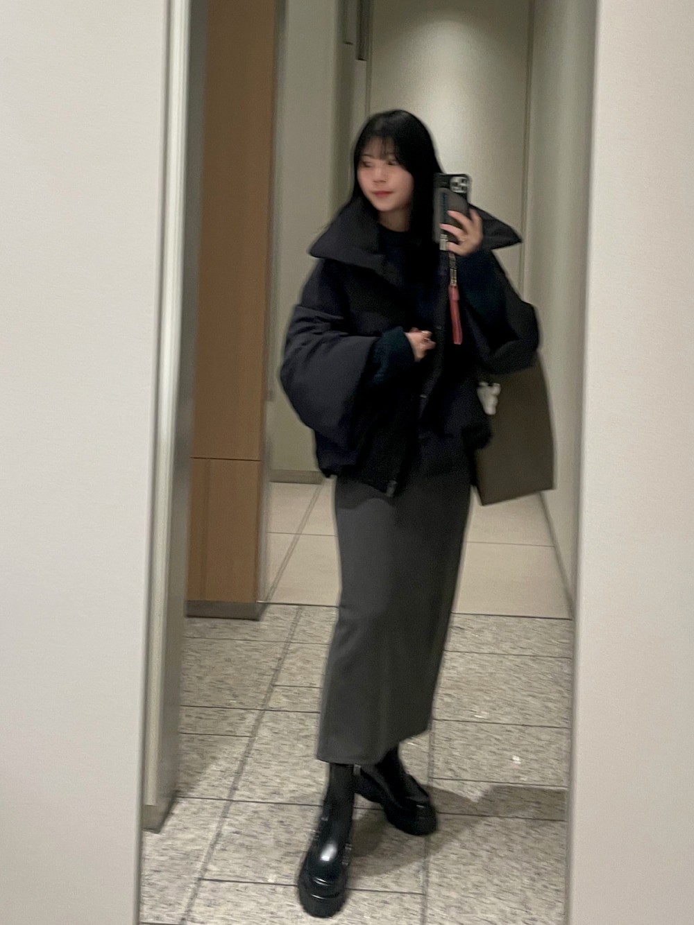 ブラック系のダウンジャケット/コート、グレー系のスカート、ブラック系のブーツを着用したレディースの冬コーディネートの1枚目の写真