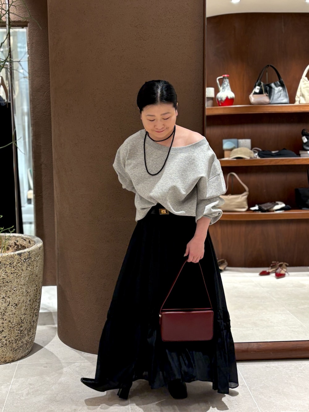 グレー系のTシャツ/カットソー、レッド系のショルダーバッグ、ブラック系のブーツを着用したレディースの冬コーディネートの1枚目の写真