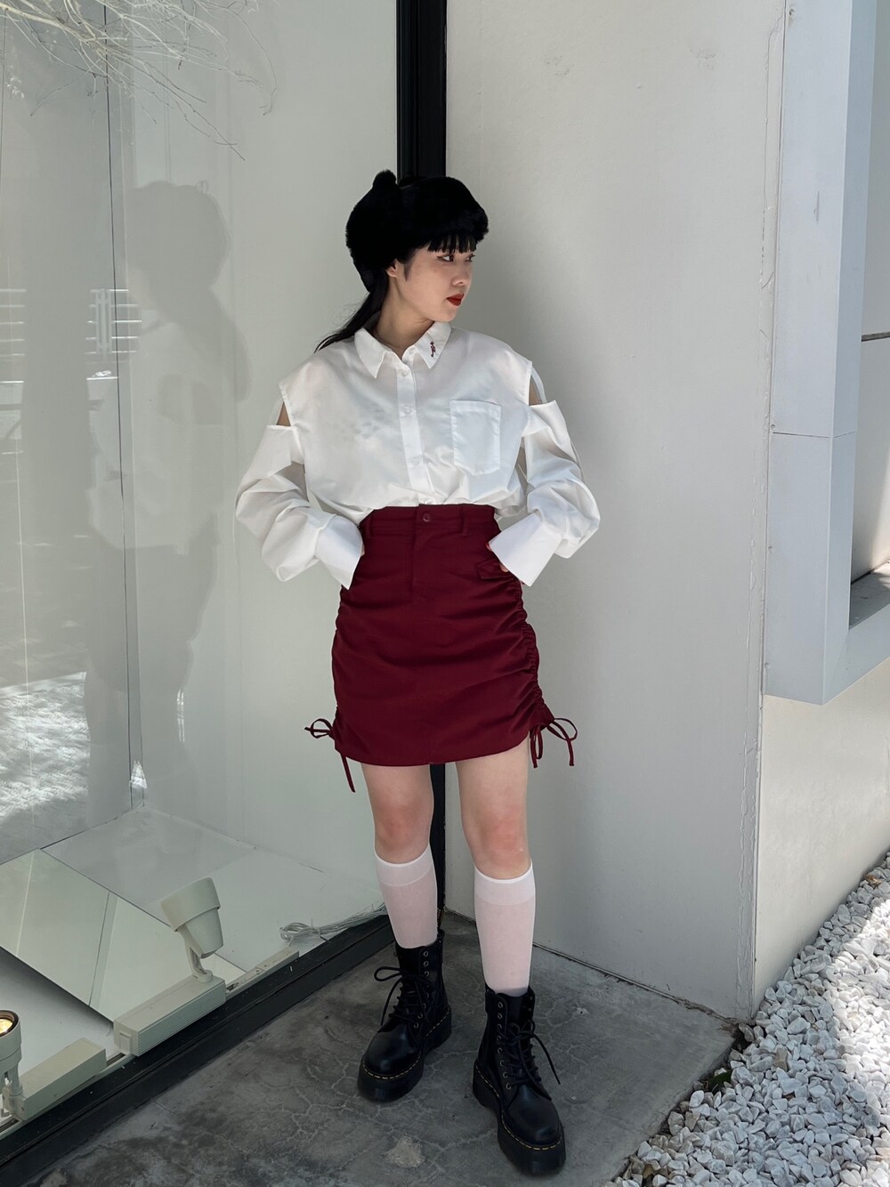 レッド系のスカート、ホワイト系のシャツ/ブラウス、ブラック系のキャップを着用したレディースの夏コーディネートの1枚目の写真