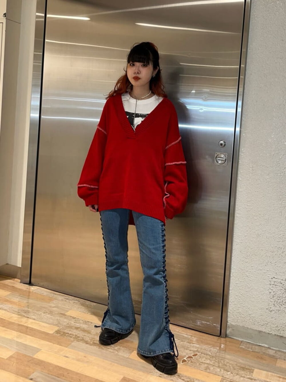 レッド系のニット/セーター、ホワイト系のTシャツ/カットソーを着用したレディースの冬コーディネートの1枚目の写真