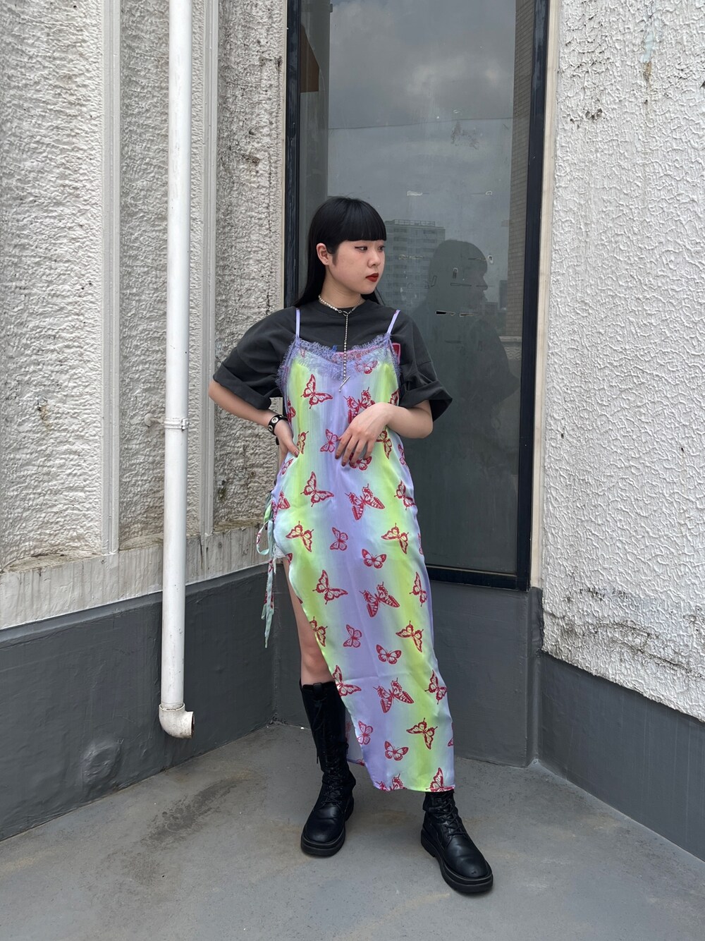 パープル系のワンピース、ブラック系のTシャツ/カットソー、ブラック系のブーツを着用したレディースの春コーディネートの1枚目の写真