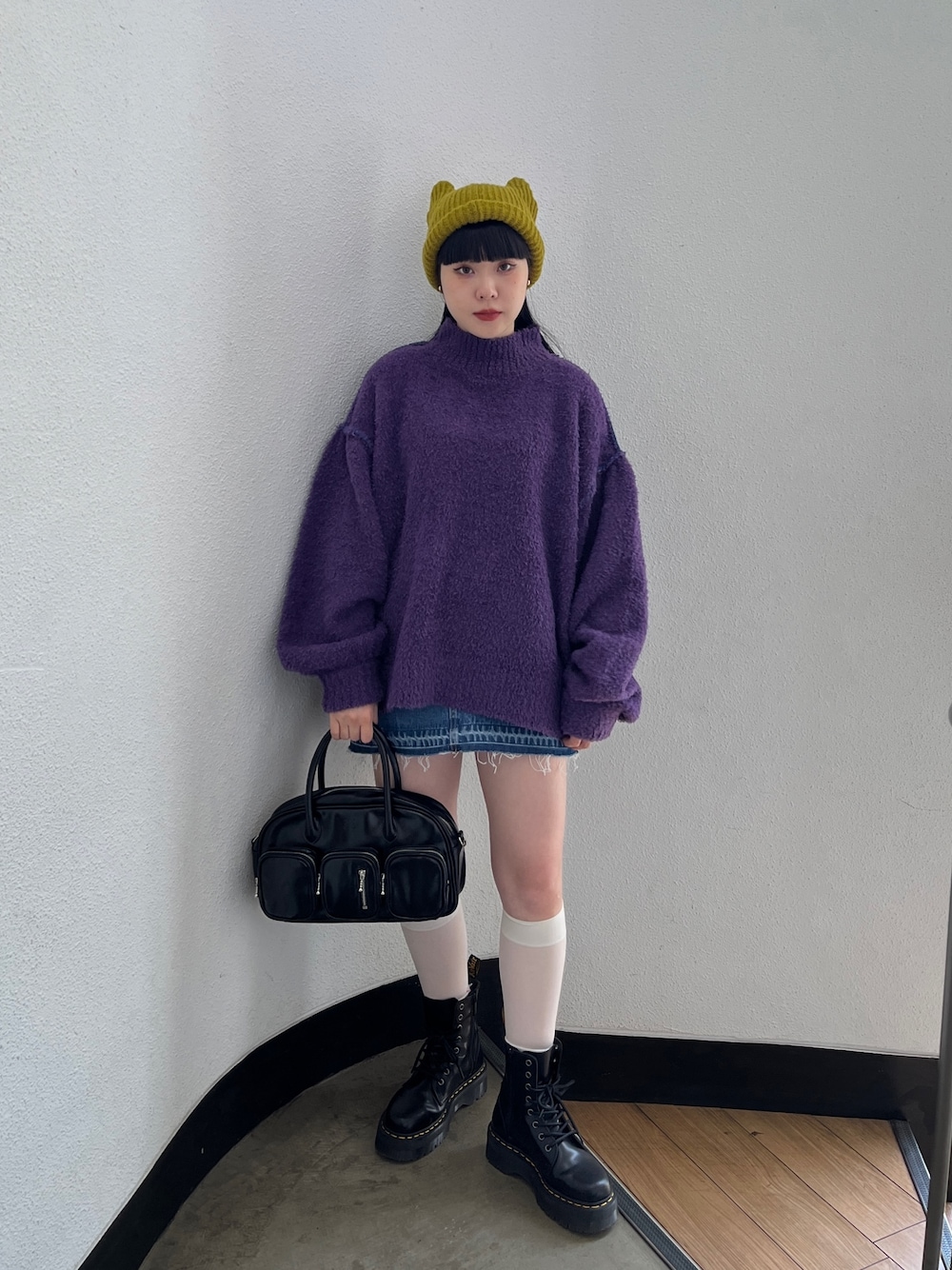 パープル系のニット/セーター、ブルー系のデニムパンツ、グリーン系のボストンバッグを着用したレディースの秋コーディネートの1枚目の写真