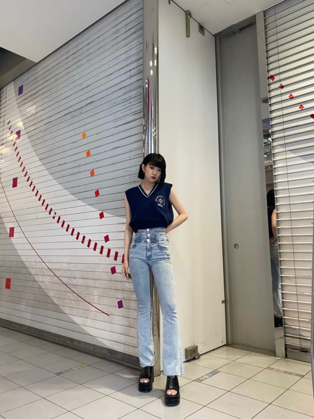 ブラック系のサンダル、ブルー系のデニムパンツ、ブルー系のベストを着用したレディースの春コーディネートの1枚目の写真