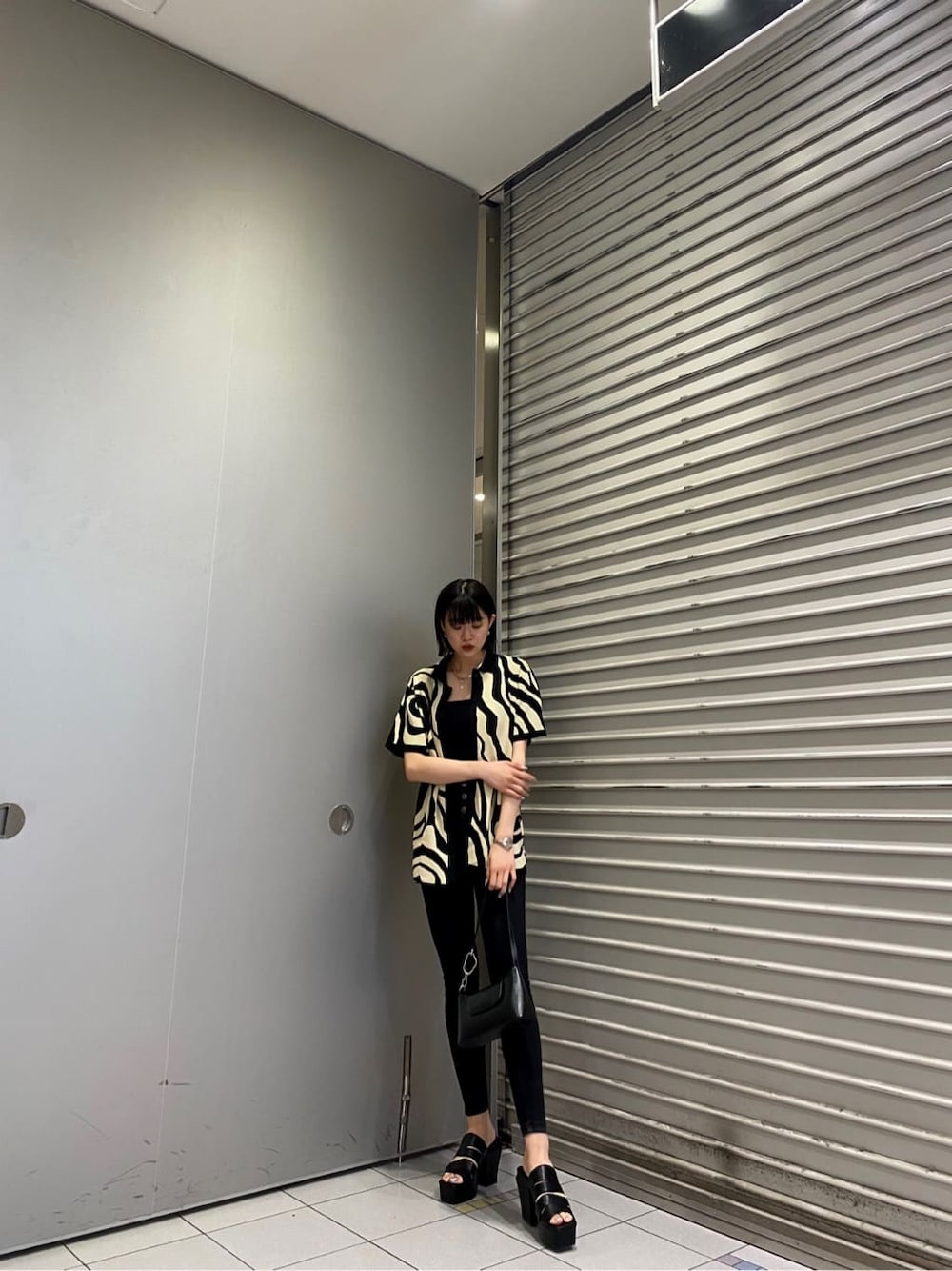 ブラック系のニット/セーター、ブラック系のサンダル、ブラック系のデニムパンツを着用したレディースの夏コーディネートの1枚目の写真