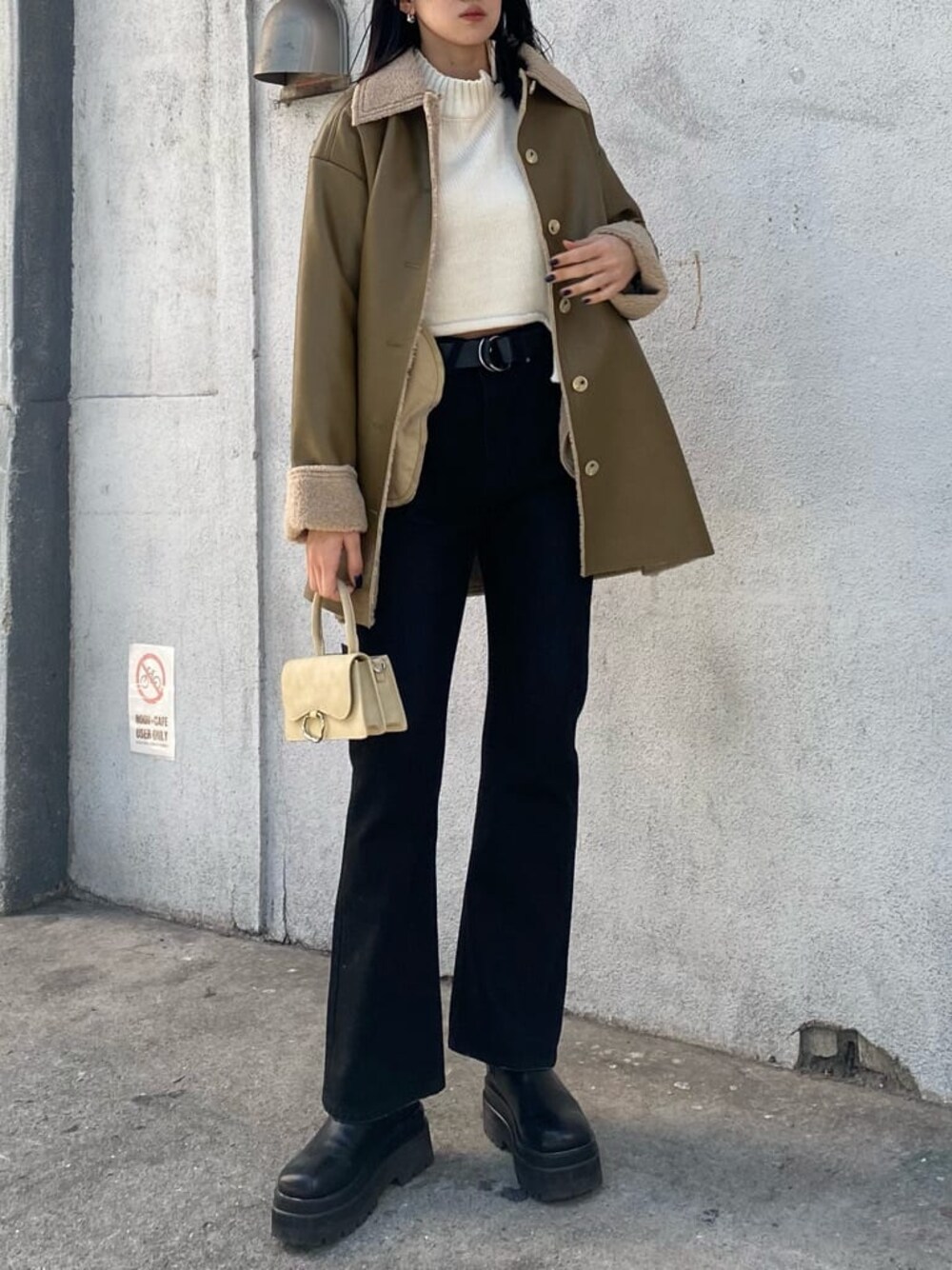 ホワイト系のニット/セーター、ホワイト系のハンドバッグ、ベージュ系のムートンコートを着用したレディースの冬コーディネートの1枚目の写真