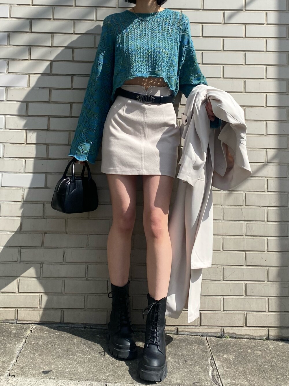 ホワイト系のスカート、ブルー系のニット/セーター、ホワイト系のトレンチコートを着用したレディースの春コーディネートの1枚目の写真
