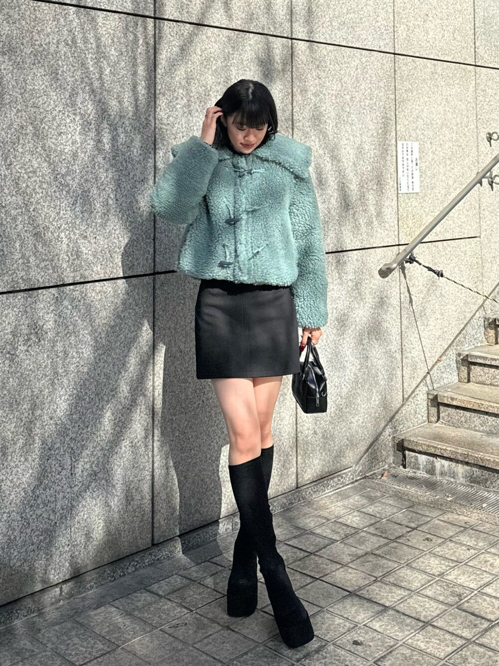 グリーン系のブルゾン、ブラック系のスカート、その他のブーツを着用したレディースの冬コーディネートの1枚目の写真