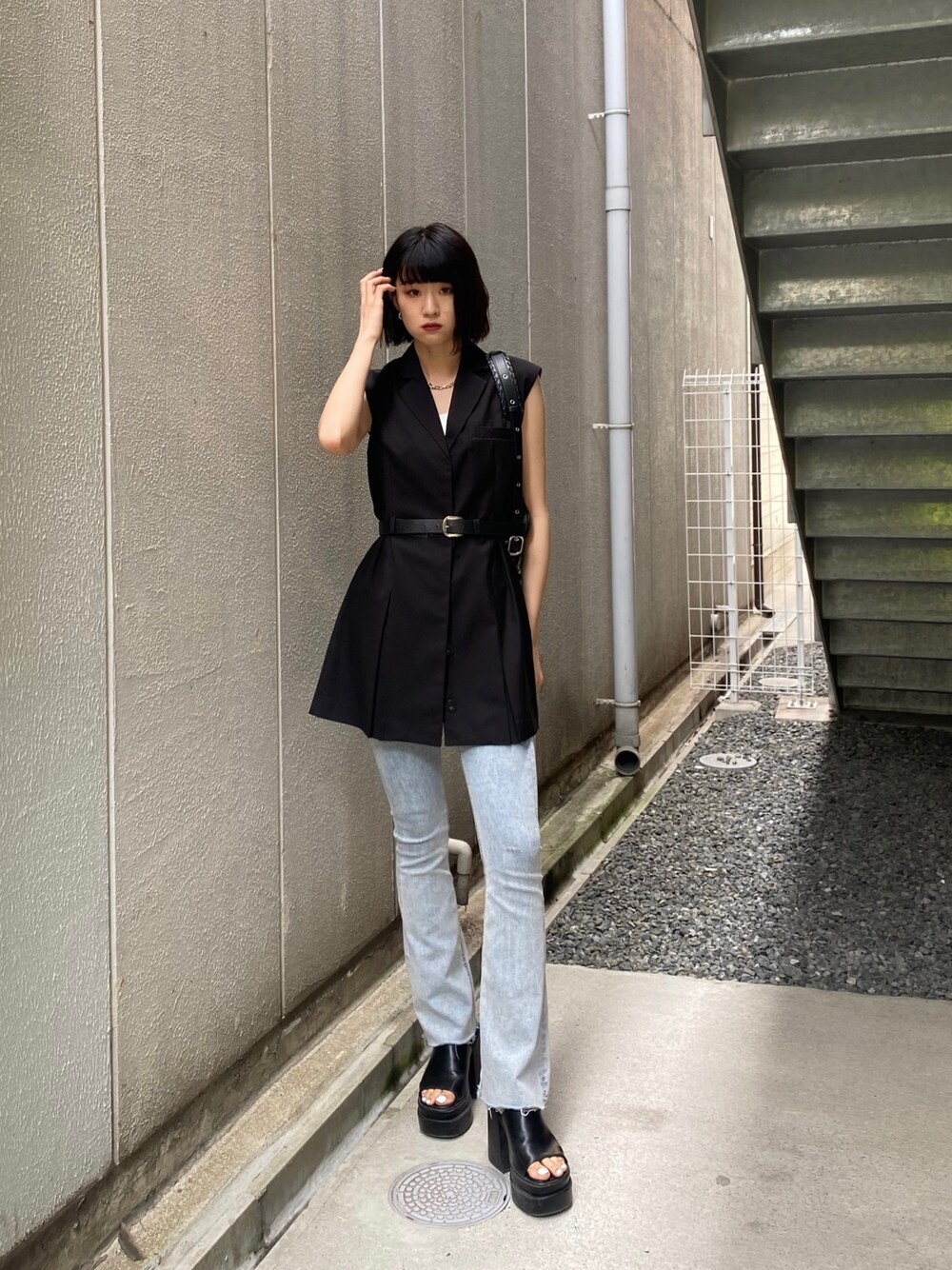 ブラック系のワンピース、ブラック系のサンダル、ブルー系のデニムパンツを着用したレディースの夏コーディネートの1枚目の写真