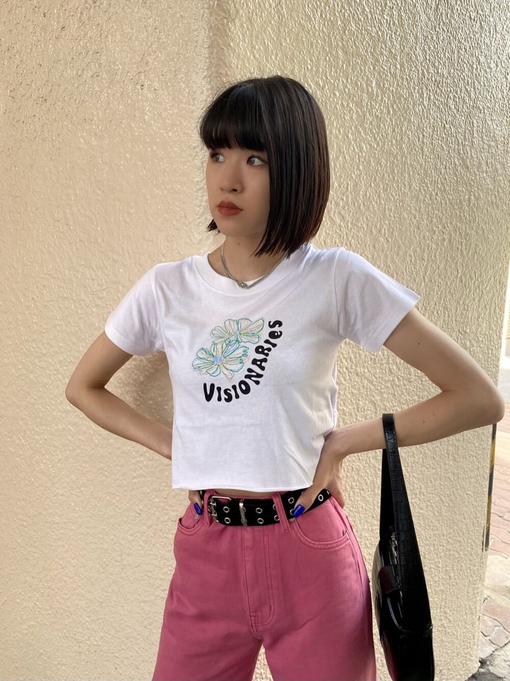 ピンク系のデニムパンツ、ブラック系のハンドバッグ、ホワイト系のTシャツ/カットソーを着用したレディースの夏コーディネートの1枚目の写真