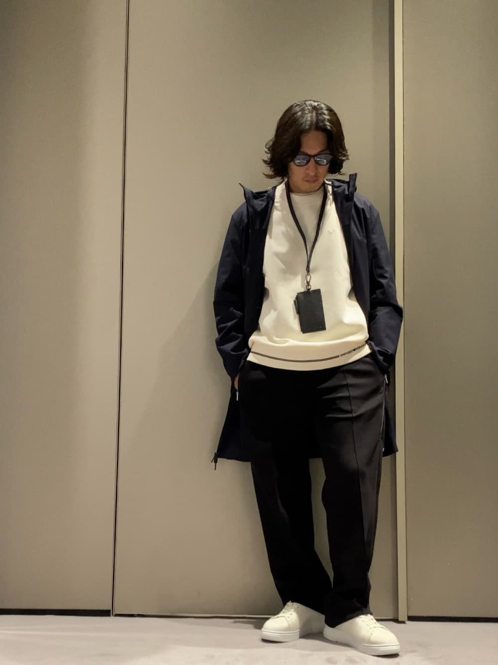 ブルー系のトレンチコート、ホワイト系のスニーカー、ブラック系のチノパンツを着用したメンズの秋コーディネートの1枚目の写真