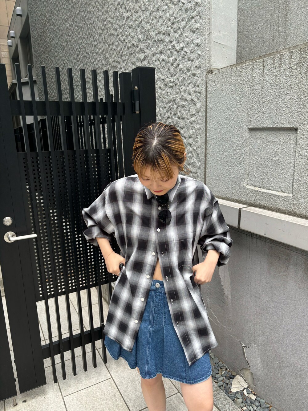 ブルー系のデニムスカート、ブラック系のシャツ/ブラウスを着用したレディースの春コーディネートの1枚目の写真