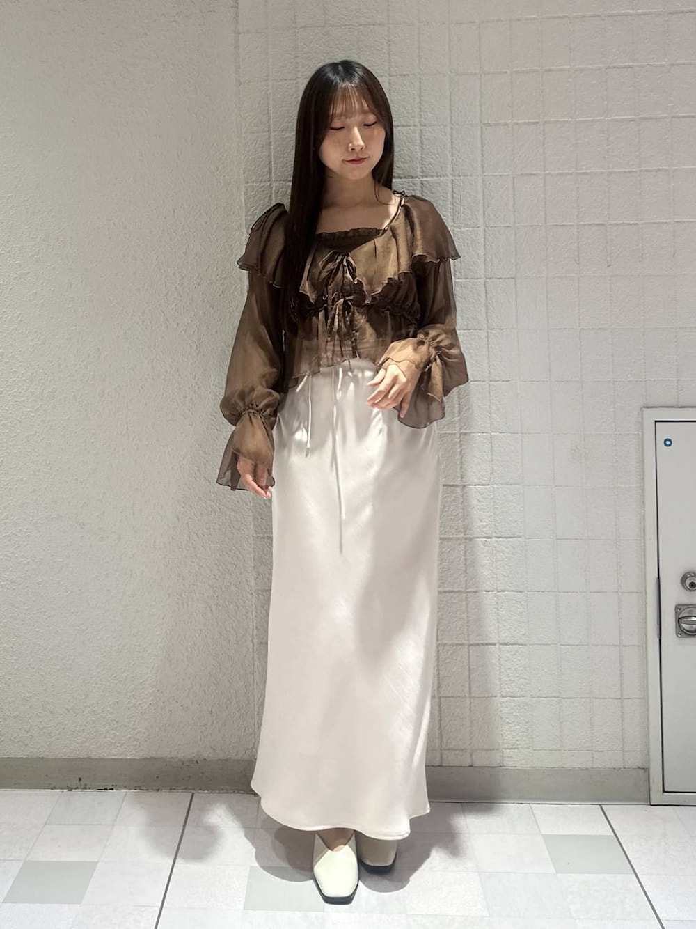 ホワイト系のスリッポン、ブラウン系のシャツ/ブラウス、ホワイト系のスカートを着用したレディースの春コーディネートの1枚目の写真