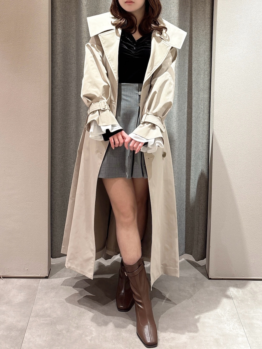ブラック系のTシャツ/カットソー、ベージュ系のトレンチコート、グレー系のスカートを着用したレディースの春コーディネートの1枚目の写真