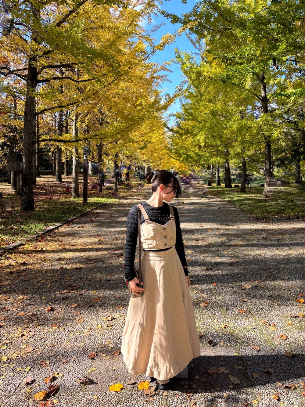 ベージュ系のスニーカー、ブラック系のTシャツ/カットソー、ベージュ系のデニムスカートを着用したレディースの秋コーディネートの1枚目の写真