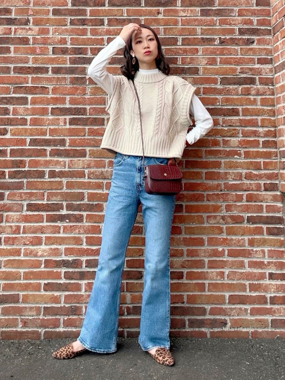 ホワイト系のベスト、ホワイト系のTシャツ/カットソー、ブルー系のデニムパンツを着用したレディースの秋コーディネートの1枚目の写真