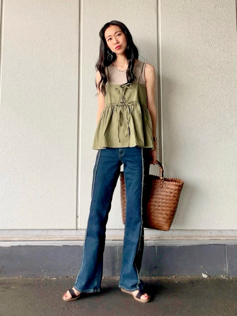 グリーン系のベスト、ベージュ系のタンクトップ、ブルー系のデニムパンツを着用したレディースの夏コーディネートの1枚目の写真