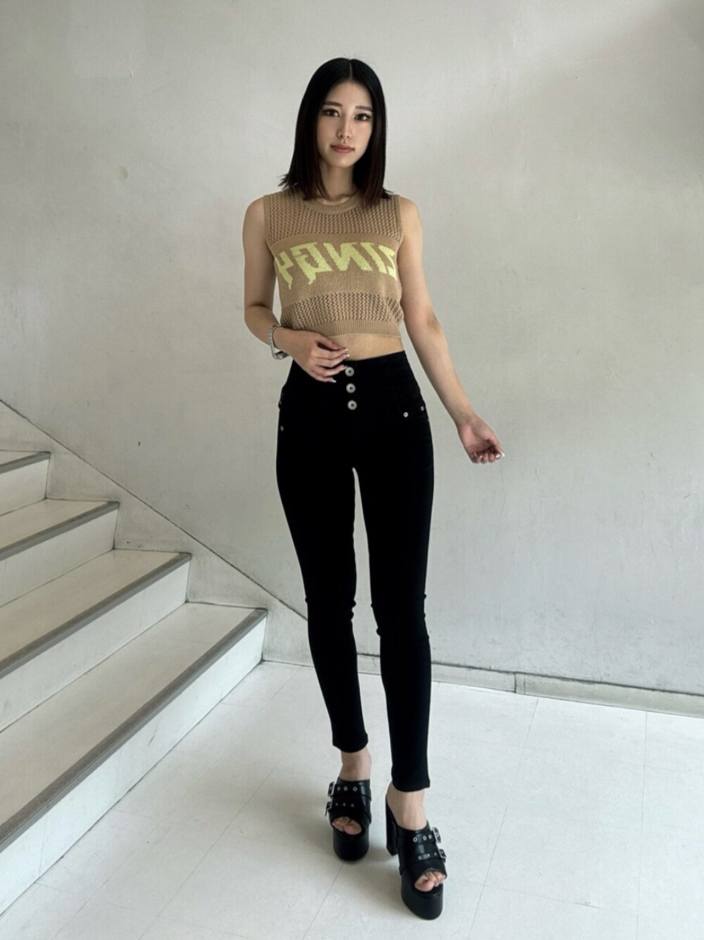 ブラック系のデニムパンツ、ベージュ系のタンクトップ、ブラック系のサンダルを着用したレディースの夏コーディネートの1枚目の写真