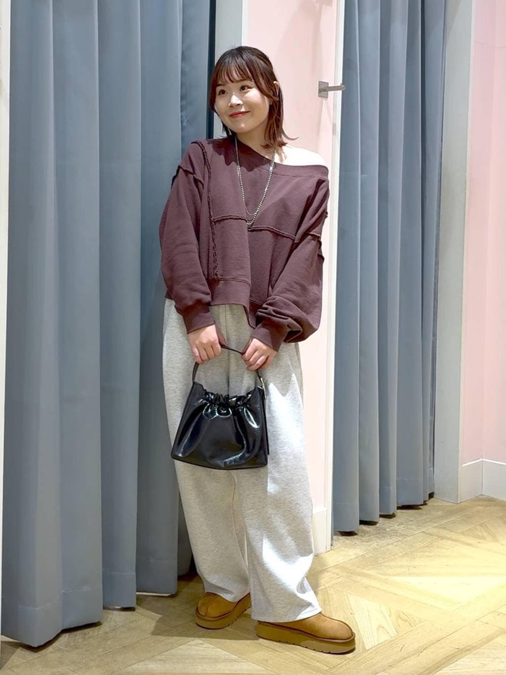 ブラウン系のスウェット、グレー系のスウェットパンツ、ブラック系のショルダーバッグを着用したレディースの秋コーディネートの1枚目の写真