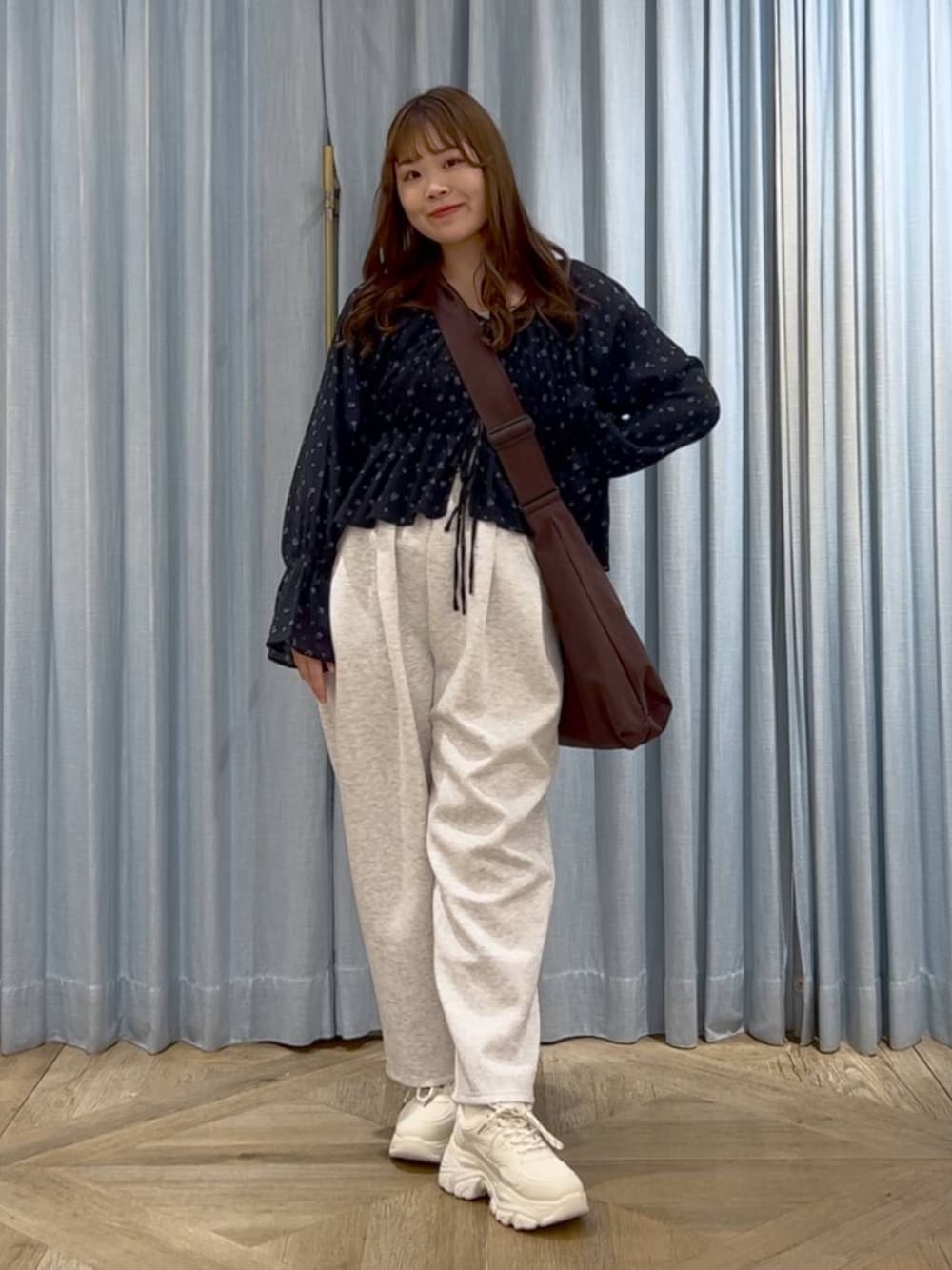 ブラウン系のショルダーバッグ、ホワイト系のスニーカー、グレー系のスウェットパンツを着用したレディースの春コーディネートの1枚目の写真