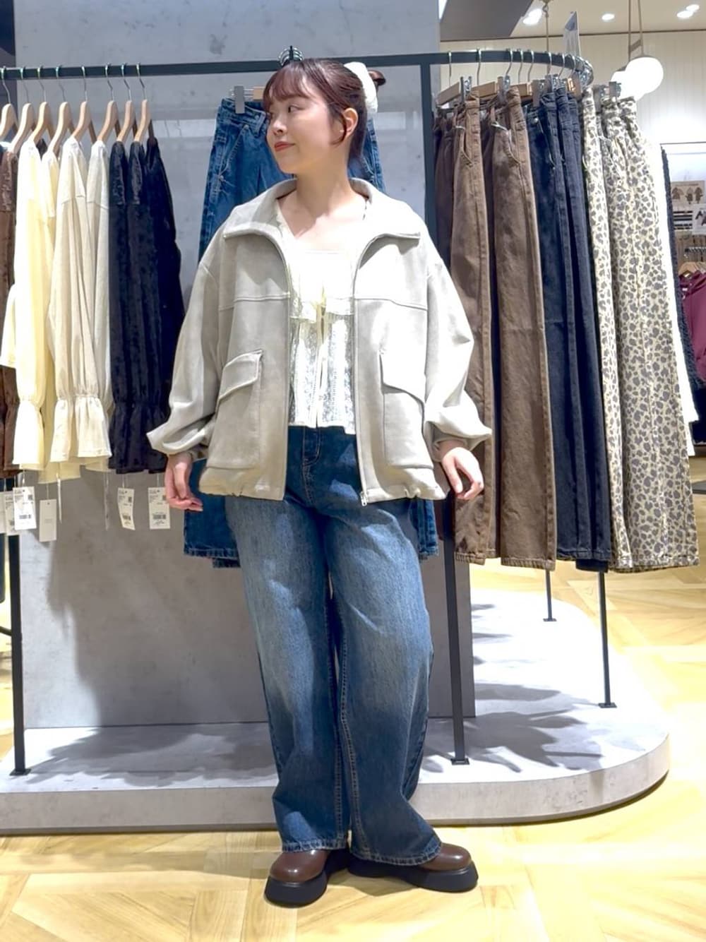ブルー系のデニムパンツ、ブラウン系のサンダル、ホワイト系のブルゾンを着用したレディースの秋コーディネートの1枚目の写真