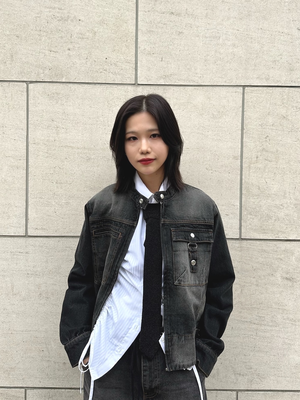 ブラック系のデニムジャケット、ブラック系のネクタイ、ブラック系のデニムパンツを着用したレディースの春コーディネートの1枚目の写真
