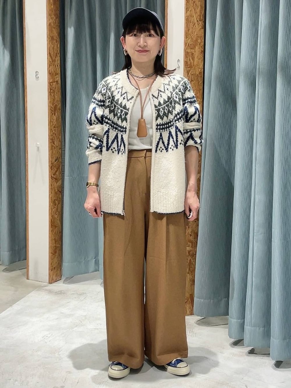 ブルー系のスニーカー、ホワイト系のカーディガン/ボレロ、ブルー系のキャップを着用したレディースの秋コーディネートの1枚目の写真