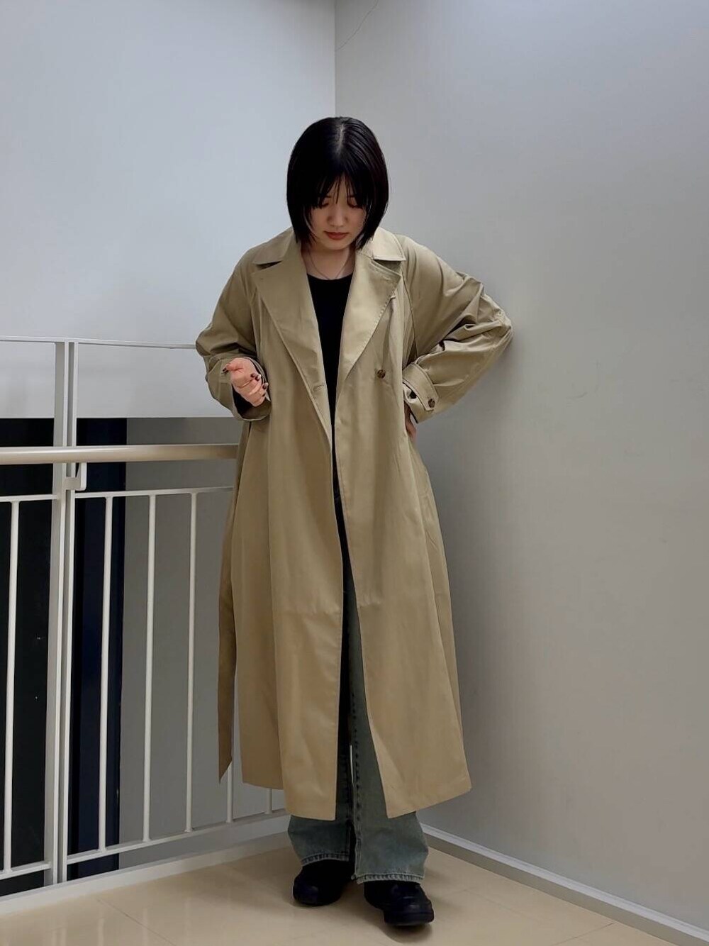 ブルー系のデニムパンツ、ベージュ系のトレンチコート、ブラック系のTシャツ/カットソーを着用したレディースの春コーディネートの1枚目の写真