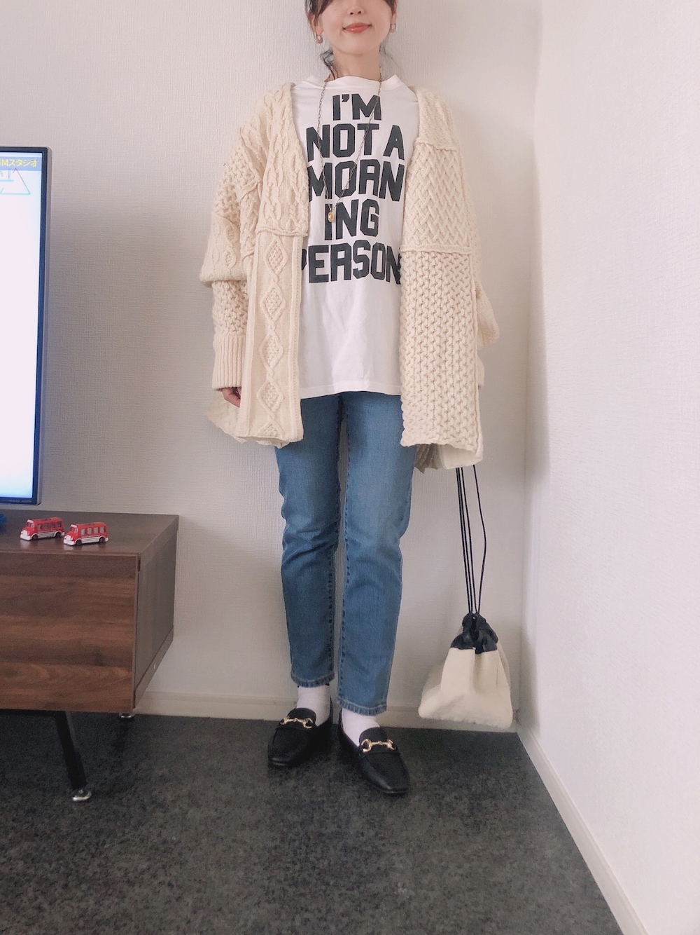 ホワイト系のカーディガン/ボレロ、ホワイト系のTシャツ/カットソー、ブラック系のローファーを着用したレディースの冬コーディネートの1枚目の写真