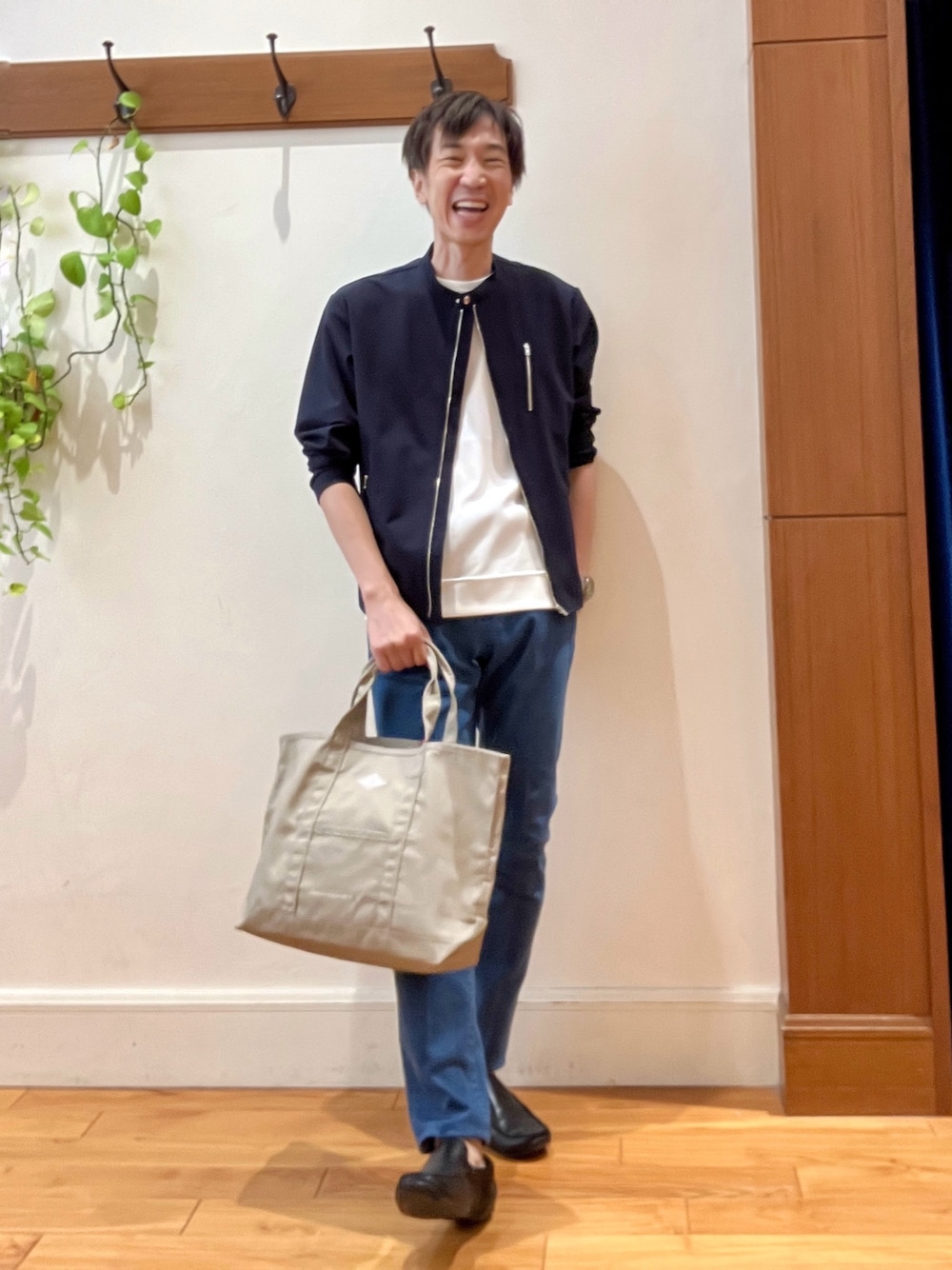 ブルー系のデニムパンツ、ベージュ系のトートバッグ、ホワイト系のTシャツ/カットソーを着用したメンズの秋コーディネートの1枚目の写真