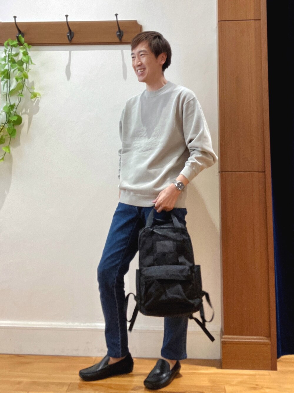 ベージュ系のスウェット、ブルー系のデニムパンツ、ブラック系のバックパック/リュックを着用したメンズの秋コーディネートの1枚目の写真