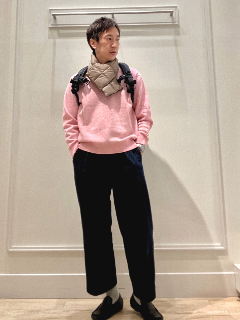 ピンク系のニット/セーター、ブラック系のバックパック/リュック、グリーン系のマフラーを着用したメンズの冬コーディネートの1枚目の写真