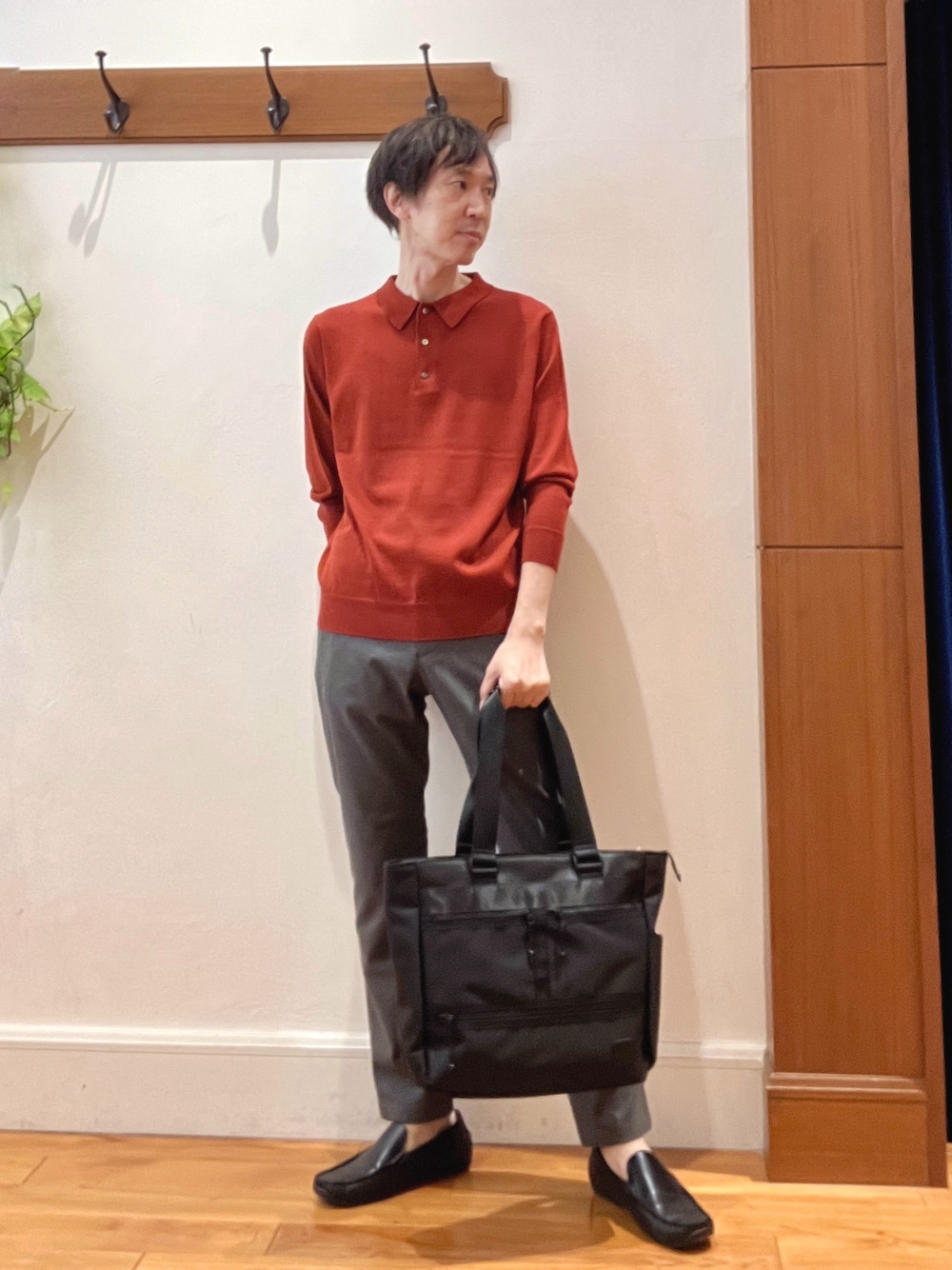 グレー系のその他パンツ、レッド系のニット/セーター、ブラック系のトートバッグを着用したメンズの秋コーディネートの1枚目の写真