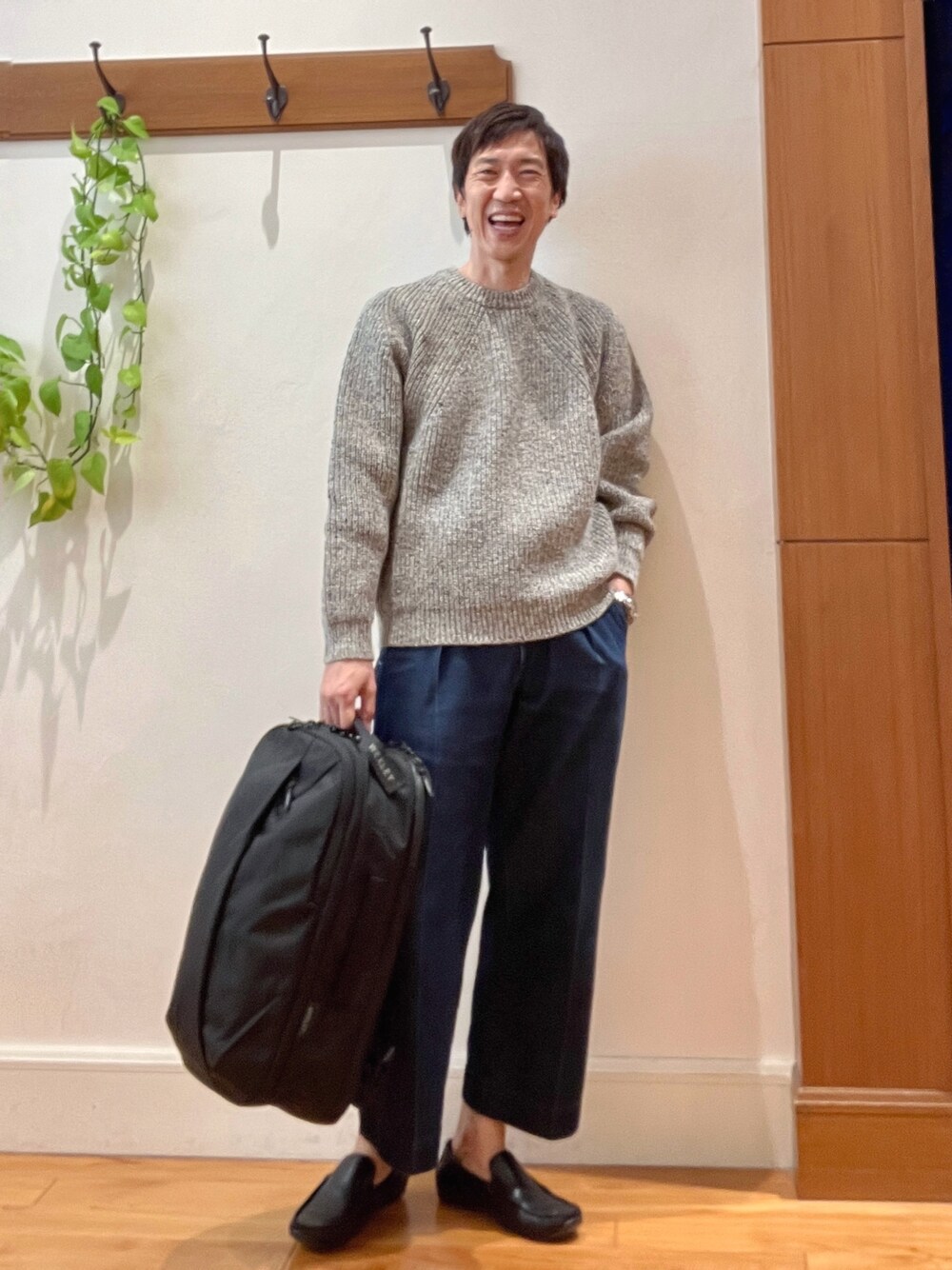 グレー系のニット/セーター、ブラック系のバックパック/リュックを着用したメンズの秋コーディネートの1枚目の写真