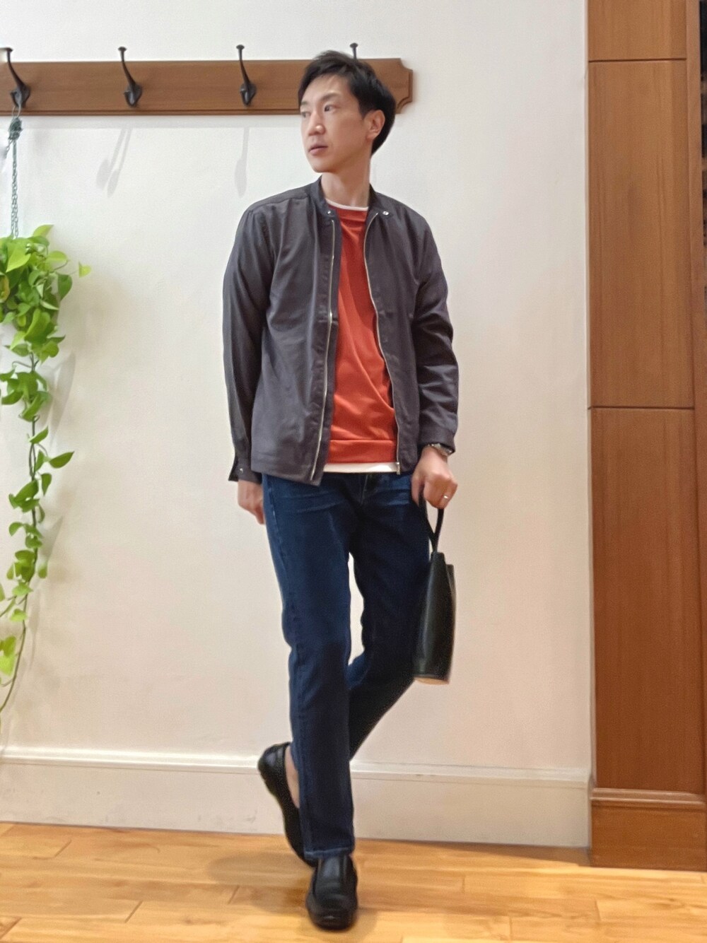 ブルー系のデニムパンツ、ブラック系のハンドバッグ、オレンジ系のTシャツ/カットソーを着用したメンズの秋コーディネートの1枚目の写真