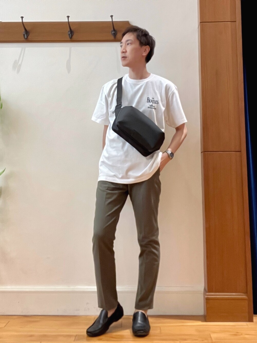グリーン系のチノパンツ、ブラック系のショルダーバッグ、ホワイト系のTシャツ/カットソーを着用したメンズの春コーディネートの1枚目の写真