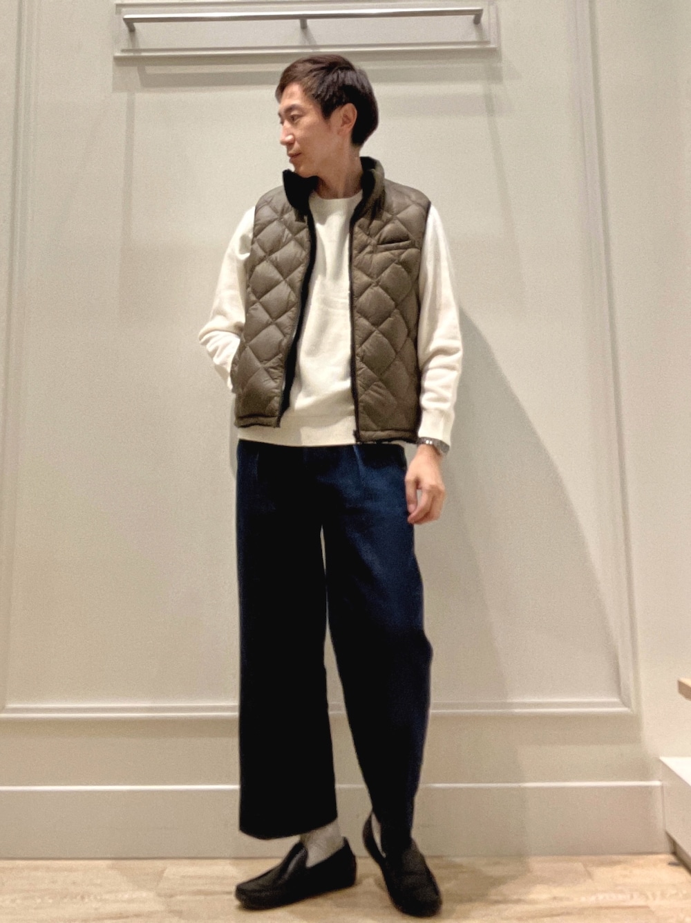 グリーン系のダウンベスト、ホワイト系のニット/セーターを着用したメンズの冬コーディネートの1枚目の写真