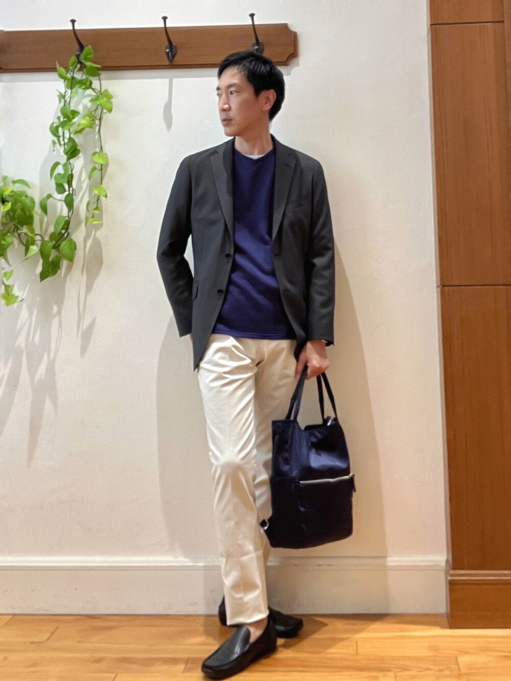 パープル系のニット/セーター、ホワイト系のチノパンツ、ブルー系のトートバッグを着用したメンズの秋コーディネートの1枚目の写真