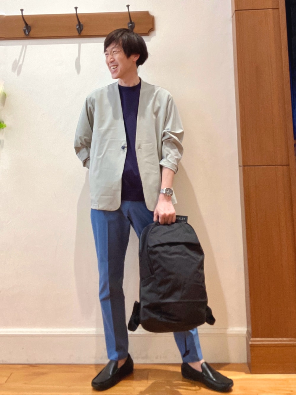 ブラック系のバックパック/リュック、ブルー系のチノパンツ、ブルー系のTシャツ/カットソーを着用したメンズの春コーディネートの1枚目の写真