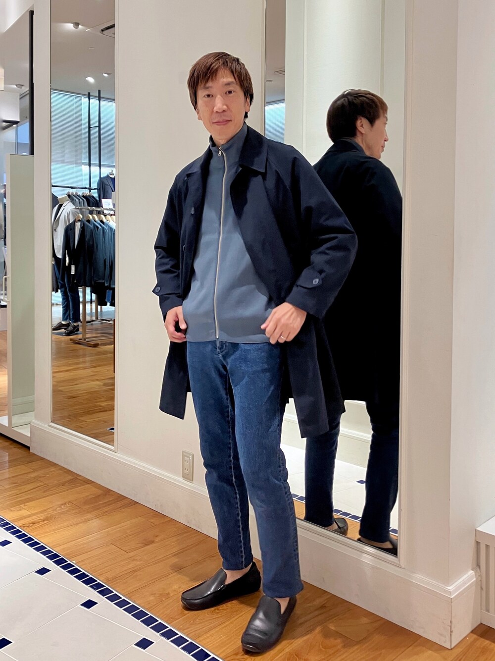 ブルー系のニット/セーター、ブルー系のステンカラーコート、ブルー系のデニムパンツを着用したメンズの秋コーディネートの1枚目の写真