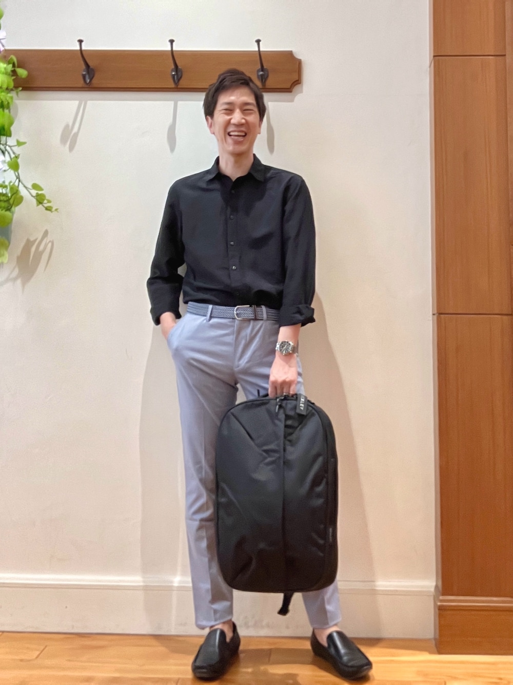ブラック系のシャツ/ブラウス、ブルー系のチノパンツ、ブラック系のバックパック/リュックを着用したメンズの春コーディネートの1枚目の写真